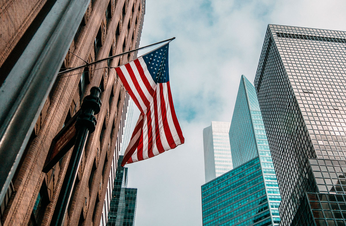 usa-united-states-america-flag-flagpole-near-skyscrapers-cloudy-sky